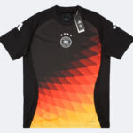 Adidas Germany national football team jersey: black base with orange–yellow geometric gradient pattern on the front, crest with five stars above it, and a attached tag.