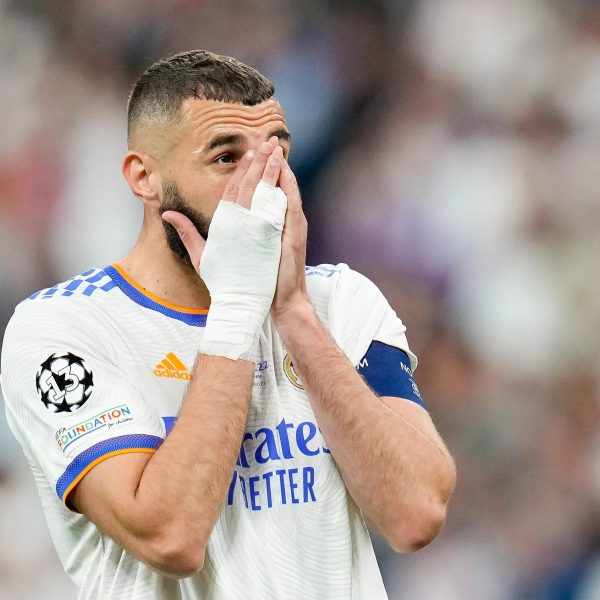 Soccer player with taped hands covering his face during a match.