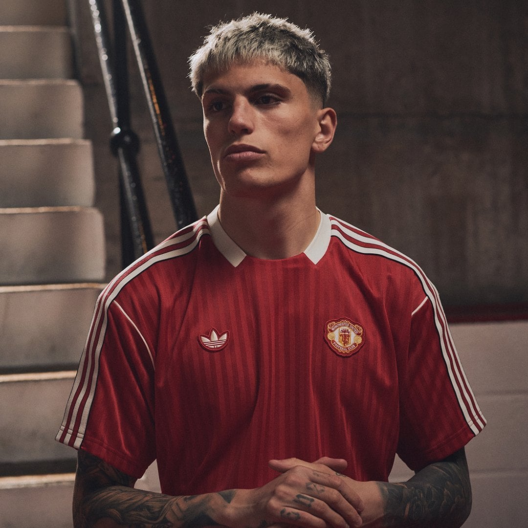 Gjq5SHLbwAAXoEZ | UAE SPORT STORE Young man in a red Manchester United jersey with Adidas branding, standing in a dim stairwell with hands clasped.