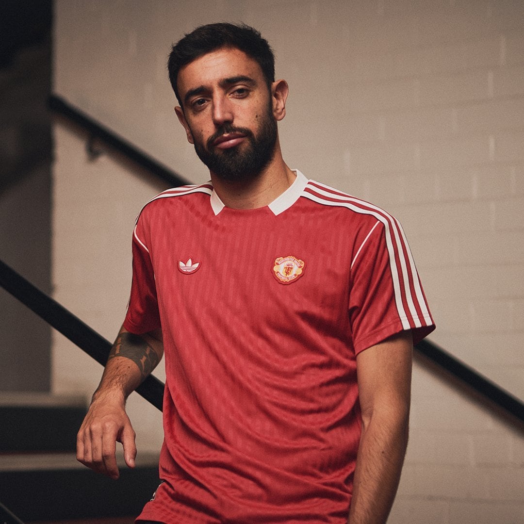 Gjq5X0BaQAEiGLj | UAE SPORT STORE Man in a red Manchester United jersey posing indoors against a neutral wall backdrop, looking at the camera with a relaxed expression.