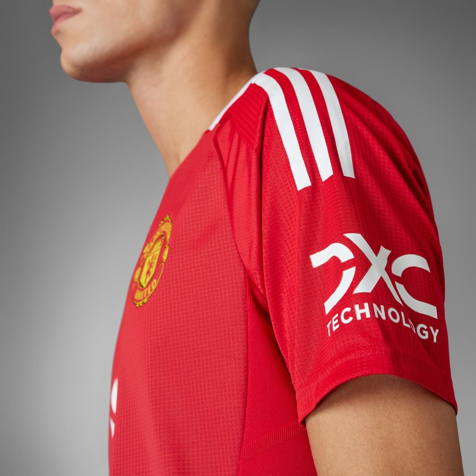 GtNotw0bzPpdgdy | UAE SPORT STORE Close-up of a red Manchester United jersey with white shoulder stripes and the club crest.