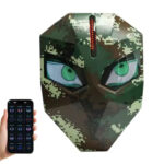 Camouflage digital mask with glowing green eyes and a vertical LED strip on the forehead, controlled by a smartphone app shown to the left.