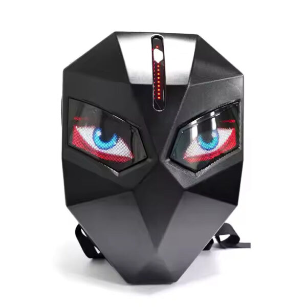 Black geometric mask with angular facets, glowing blue and red LED eyes, and a vertical LED strip on the forehead, placed on a white surface with straps visible underneath.