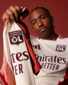 Close-up of a person holding a white and red Olympique Lyonnais jersey, with the OL crest visible on the sleeve.