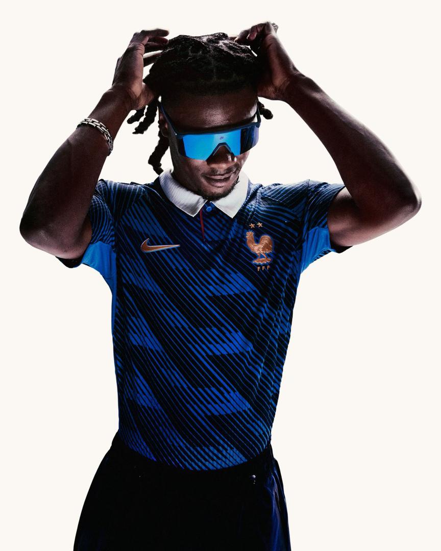 HE5lhFiXgAAQ7Sv | UAE SPORT STORE Man in a blue France national team football jersey with Nike logo, wearing futuristic blue sunglasses and adjusting his hair.