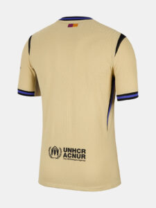 Beige sports jersey back view with UNHCR logo and text near hem: 'UNHCR ACNUR The UN Refugee Agency' and small flag at neck.