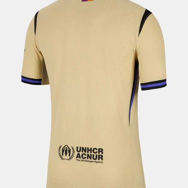 Beige sports jersey back view with UNHCR logo and text near hem: 'UNHCR ACNUR The UN Refugee Agency' and small flag at neck.