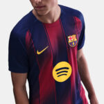 Close-up of a FC Barcelona soccer jersey featuring red and blue stripes, a yellow Nike swoosh, the club crest, and a large Spotify logo front and center.