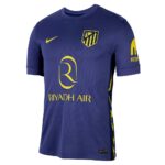 Blue Atlético Madrid jersey with yellow Riyadh Air sponsor, Nike swoosh, and club crest on the chest.