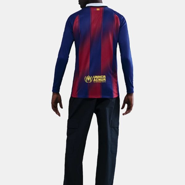 Back view of a man in a blue and red striped long-sleeve shirt with UNHCR logo on the lower back, wearing black cargo pants and white sneakers.