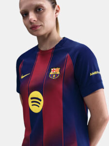 Close-up of a person wearing a FC Barcelona football jersey with blue and red vertical stripes, crest on the left chest, and a yellow Nike swoosh.