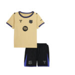 Beige soccer jersey with blue trim and team crest, paired with black shorts that have blue panels.