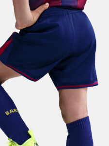 Close-up of navy athletic shorts with red trim, worn with matching blue socks and neon-yellow shoes