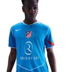 Person wearing a bright blue soccer jersey with Riyadh Air logo and an Atletico Madrid crest on the chest, white trim visible at collar and sleeves.