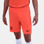 Male athlete wearing bright orange soccer shorts with FC Barcelona crest on the left leg and a black Nike swoosh, white socks visible.