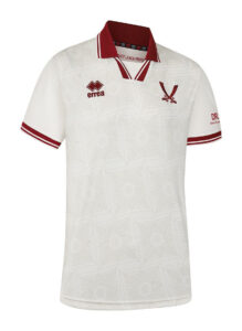 White polo shirt with maroon collar and cuffs featuring geometric pattern; logos: Errea and a V-shaped emblem on chest.