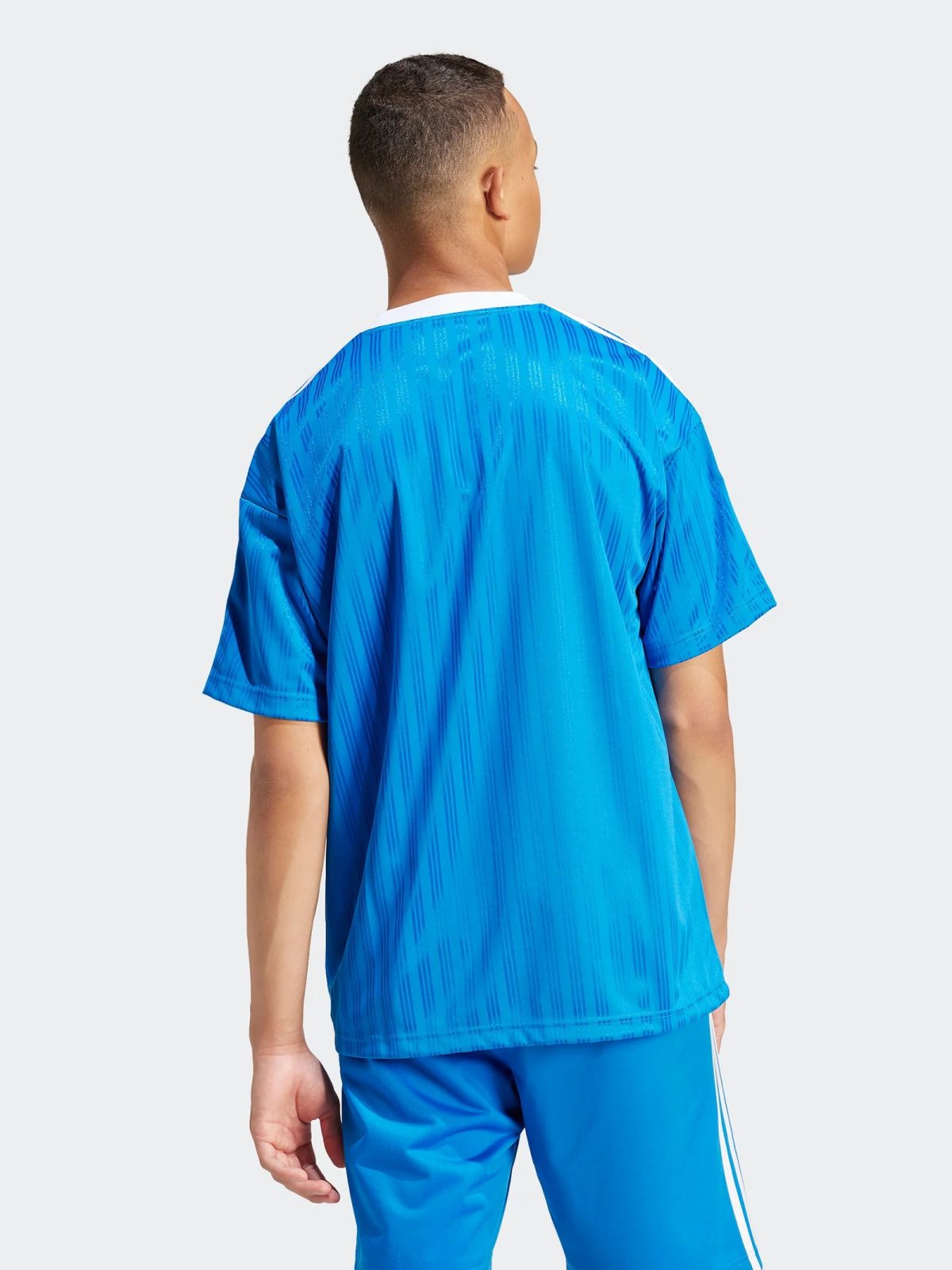 Back view of a person wearing a bright blue athletic jersey and matching shorts, seen from the shoulders down to mid-thighs.