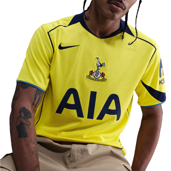 Person wearing a bright yellow soccer jersey with a crest on the chest and the large 'AIA' sponsor logo across the front.