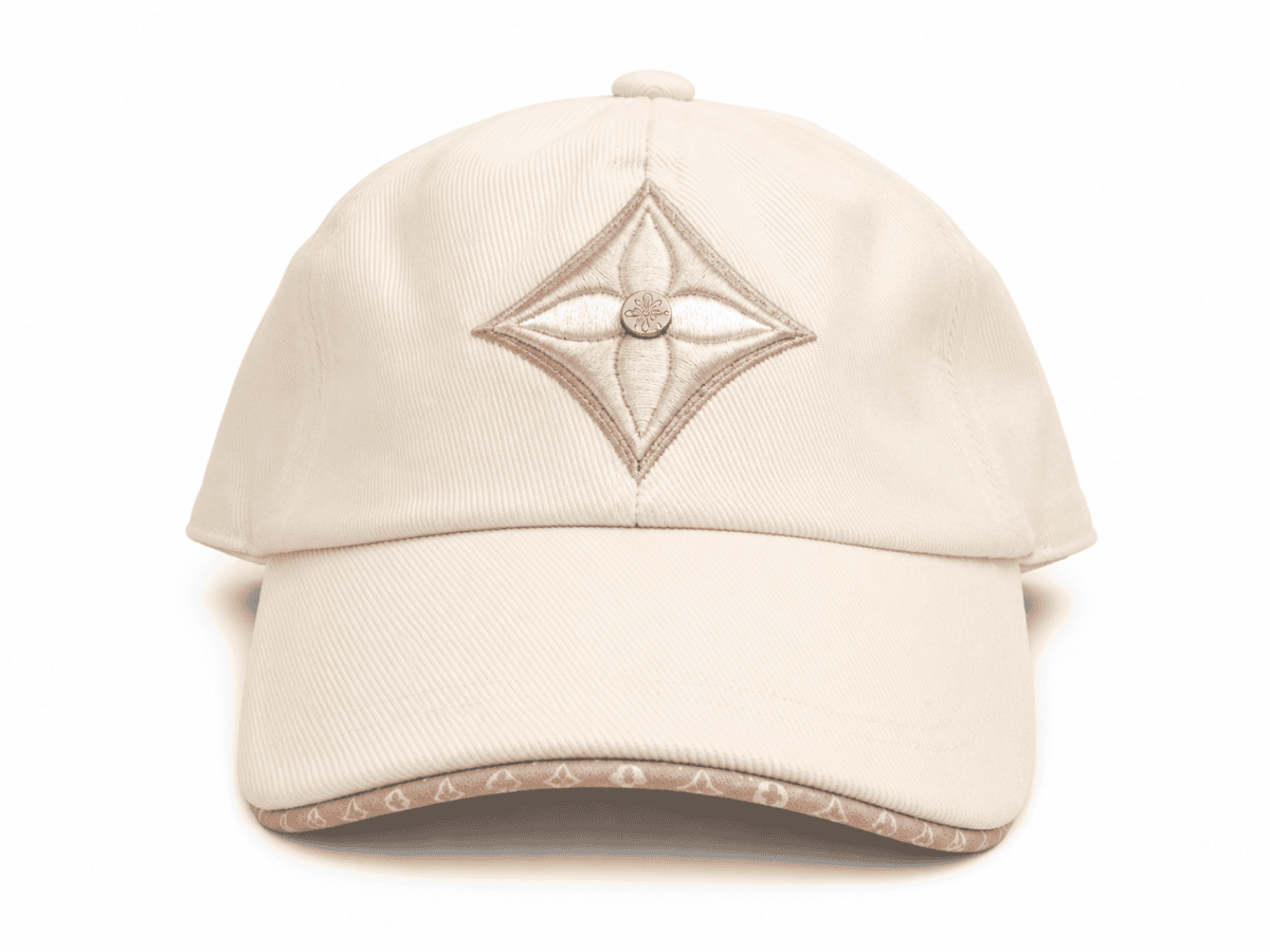 Beige baseball cap with a diamond-shaped pink embroidery on the front, centered by a small gold button on the crown.
