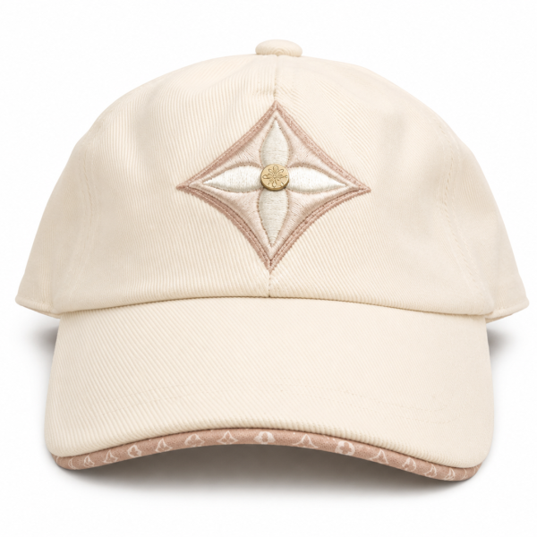 Beige baseball cap with a diamond-shaped pink embroidery on the front, centered by a small gold button on the crown.