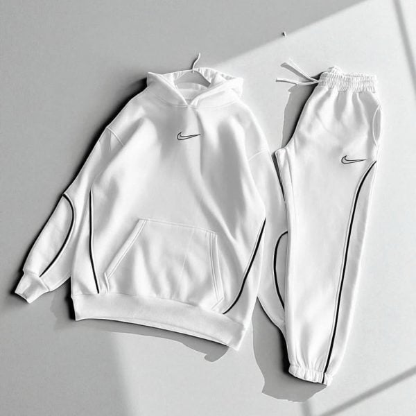 White Nike tracksuit: a hoodie with front pocket and drawstring hood paired with matching jogger pants featuring black piping accents.