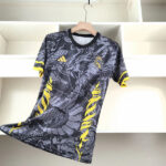 Gray Real Madrid football jersey on a hanger with a dragon-inspired pattern, yellow accents, and the club crest visible on the chest.