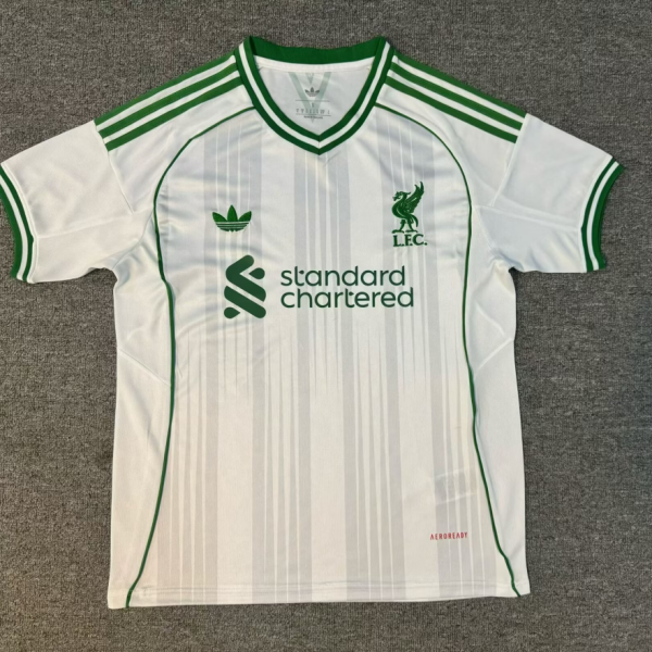 White soccer jersey with green piping, striped shoulders, and Standard Chartered sponsor logo on front
