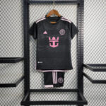 Black soccer jersey with pink accents and crest, hung on a wooden hanger with matching pink-trimmed shorts displayed below.