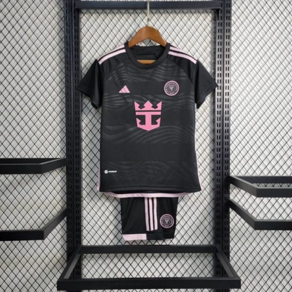 Black soccer jersey with pink accents and crest, hung on a wooden hanger with matching pink-trimmed shorts displayed below.