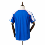Back view of a royal blue athletic jersey with white shoulder panels and red piping, on a mannequin.