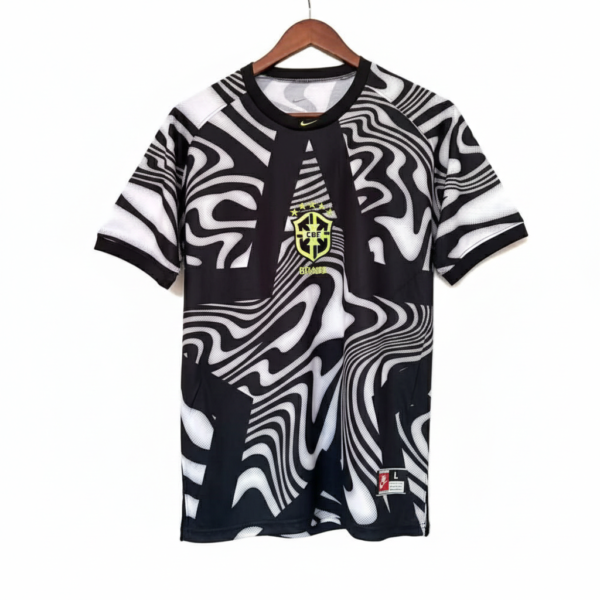 Black and white abstract patterned soccer jersey with Brazil crest on the chest, hanging on a wooden hanger, against a white background.