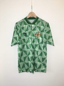 IMG_6512-scaled_0d9a8a78-b80e-467d-b0e9-72b523dcd294 | UAE SPORT STORE Green football jersey with a white geometric triangle pattern, Umbro logo, and Irish Football Association crest on the chest.