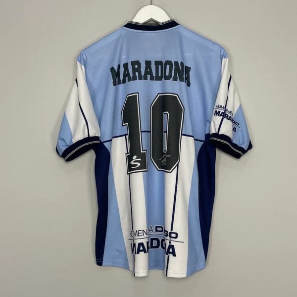 Light blue and white striped soccer jersey hanging on a white hanger, back shows 'MARADONA' and the number 10.