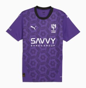 Purple soccer jersey with a geometric hexagon pattern, white Puma logo, Al Hilal crest, and 'SAVVY GAMES GROUP' text on the front.