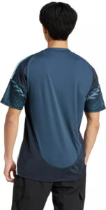 Back view of a man wearing a blue athletic t-shirt with dark panels and curved hem, standing with arms relaxed.