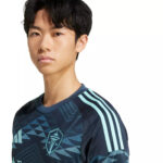 Young man wearing a dark blue geometric-pattern athletic jersey with light blue stripes on the shoulders, looking at the camera.