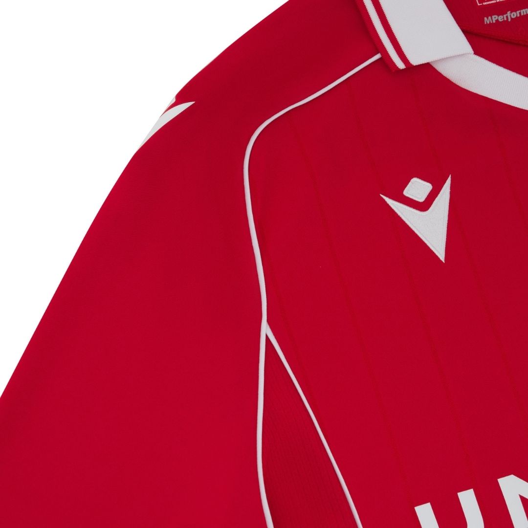 J7 | UAE SPORT STORE Close-up of a red sports jersey with white piping and a white diamond-shaped logo on the chest area.