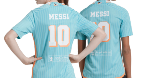 Two soccer players seen from behind in light-blue jerseys with 'MESSI' and numbers 10 and 20; sponsor logos appear on the lower back.
