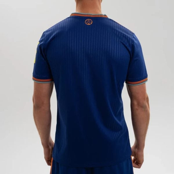 Back view of a man wearing a blue athletic jersey with orange trim and subtle pinstripes, standing with arms at his sides.