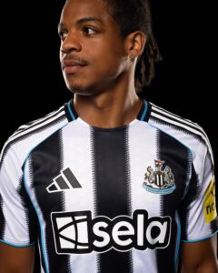 Close-up of a person wearing a black-and-white striped Newcastle United football jersey with crest visible on the chest against a black background.