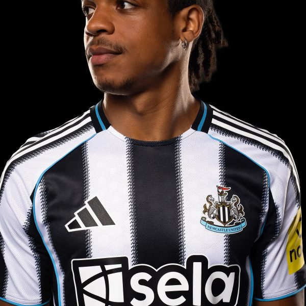 Close-up of a person wearing a black-and-white striped Newcastle United football jersey with crest visible on the chest against a black background.
