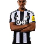 Man wearing a Newcastle United football jersey with black and white vertical stripes, arms crossed in front of a white background.