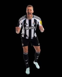 Male soccer player in a black-and-white striped jersey celebrating with fists clenched against a black background.
