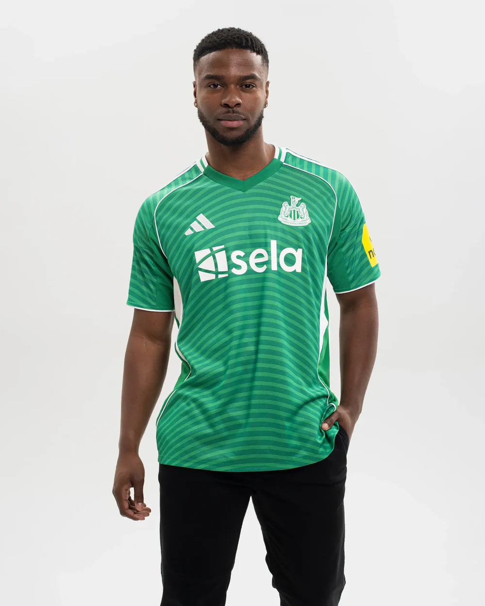 JJ2245_MOD_1 | UAE SPORT STORE Man in a green striped soccer jersey with white sponsor text 'sela' and a team crest on the chest, standing against a neutral background.