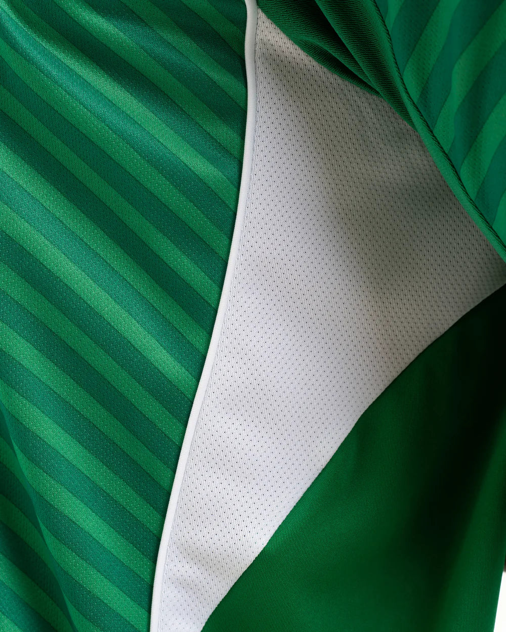 JJ2245_MOD_16 | UAE SPORT STORE Close-up of a green striped fabric with a white perforated inner lining along a seam, suggesting athletic apparel material