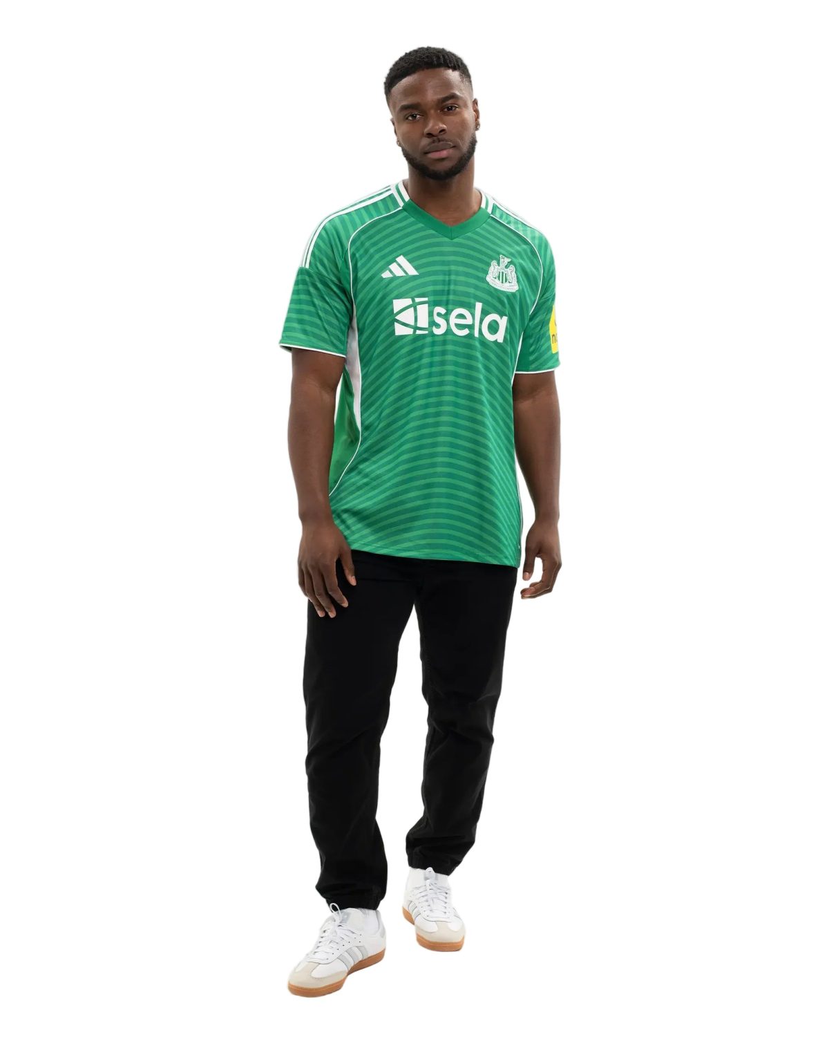 Man wearing a green striped soccer jersey with white logos, black pants, and white sneakers against a white background, facing forward.