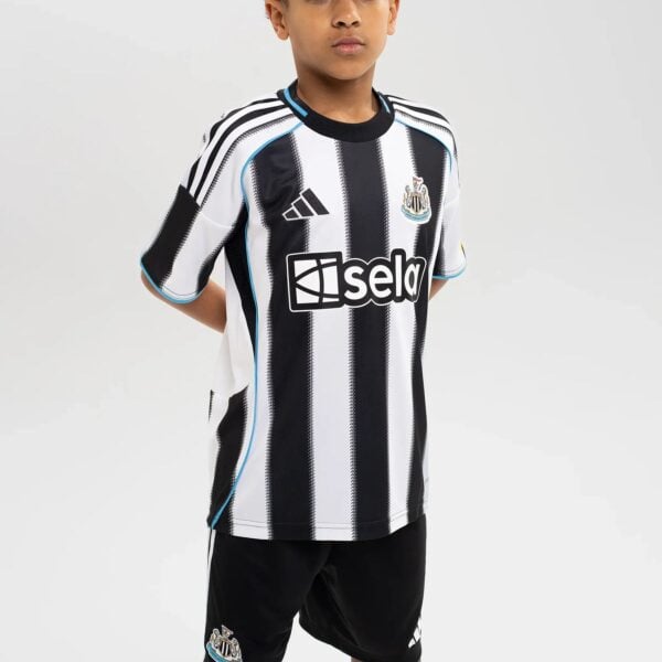 Young boy wearing a Newcastle United white-and-black striped football jersey with the club crest on the chest and Adidas logo on the other side.