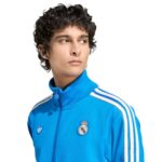 Young man in a blue track jacket with white stripes, looking to the left.