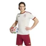 Male soccer player in a white Spain jersey holding a colorful soccer ball against a white background.