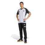 Model wearing a Juventus-inspired striped jersey and black jogger pants, standing with hands on hips.